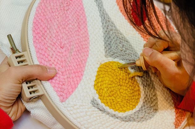 zwei Hände beim Knüpfen eines Wandteppichs mit der Punch-Needle