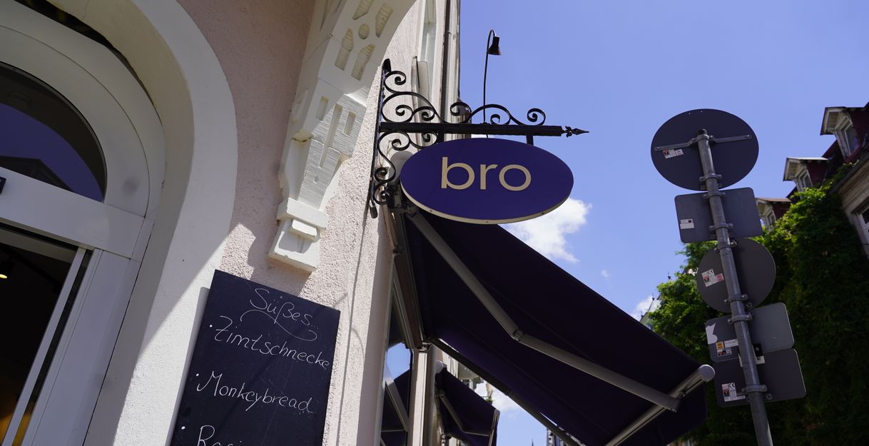 Außenansicht eines Cafés mit einem Schild 'bro' und einer Tafel mit Gebäckangeboten.