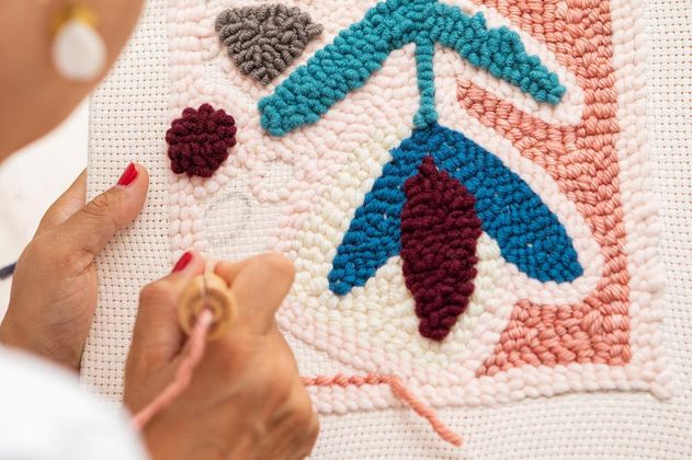 zwei Hände beim Knüpfen eines Wandteppichs mit der Punch-Needle