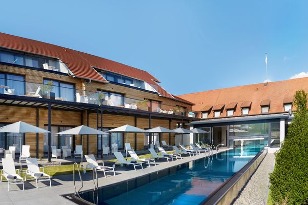 Außenansicht des Hotel Schloss Reinach mit Pool und Liegestühlen.