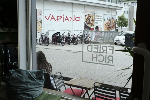 Blick aus dem Co-Working auf eine Straße mit Vapiano-Restaurant und Fahrrädern.
