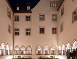 Innenhof des Augustinermuseums bei Nacht mit beleuchteten Fenstern und einem zentralen Brunnen.
