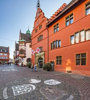 Außenansicht Altes Rathaus mit roter Fassade, in dem der Eingang der Tourist Information liegt. 