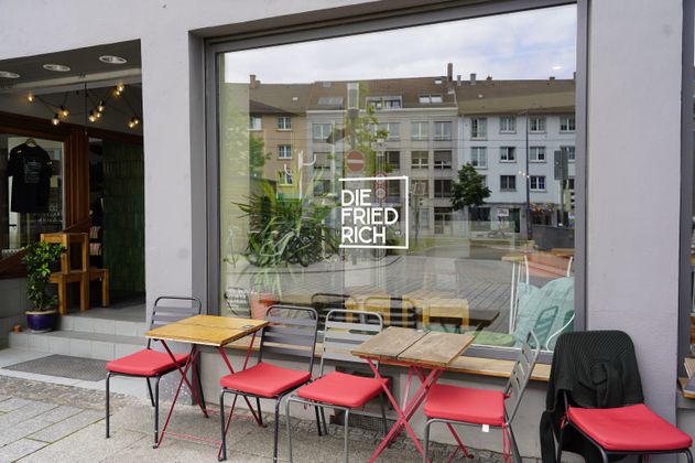 Außenansicht des Co-Workings. Rote Stühle und Holztische stehen vor dem Fenster.