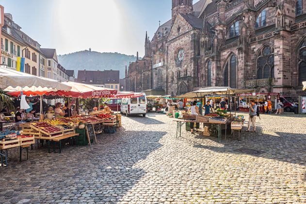 Marktstände auf dem Münsterplatz, im Hintergrund das Münster und den Schlossberg mit dem Schlossbergturm 