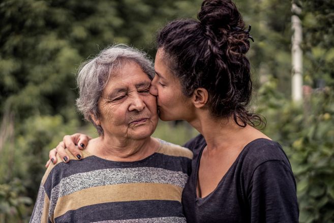 ältere Mutter, deren Tochter sie auf die Wange küsst