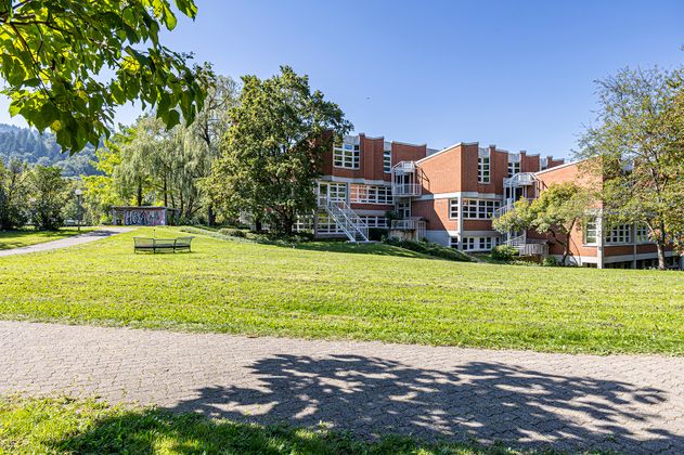 Gebäude mit roter Fassade auf begrüntem Gelände 