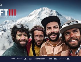 Vier Männer mit Glitzer im Gesicht vor einer schneebedeckten Berglandschaft 