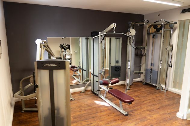 Fitnessraum mit verschiedenen Trainingsgeräten und Spiegeln.