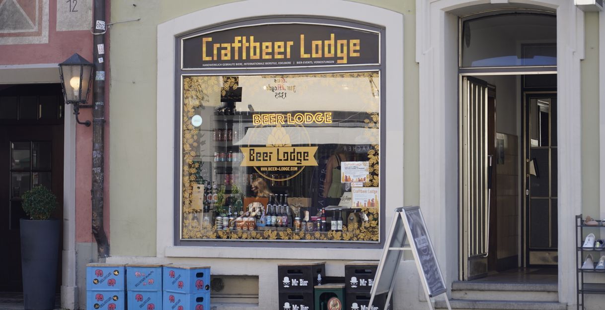 Außenansicht der Craftbeer Lodge in Freiburg mit Schaufenster und Bierkisten.