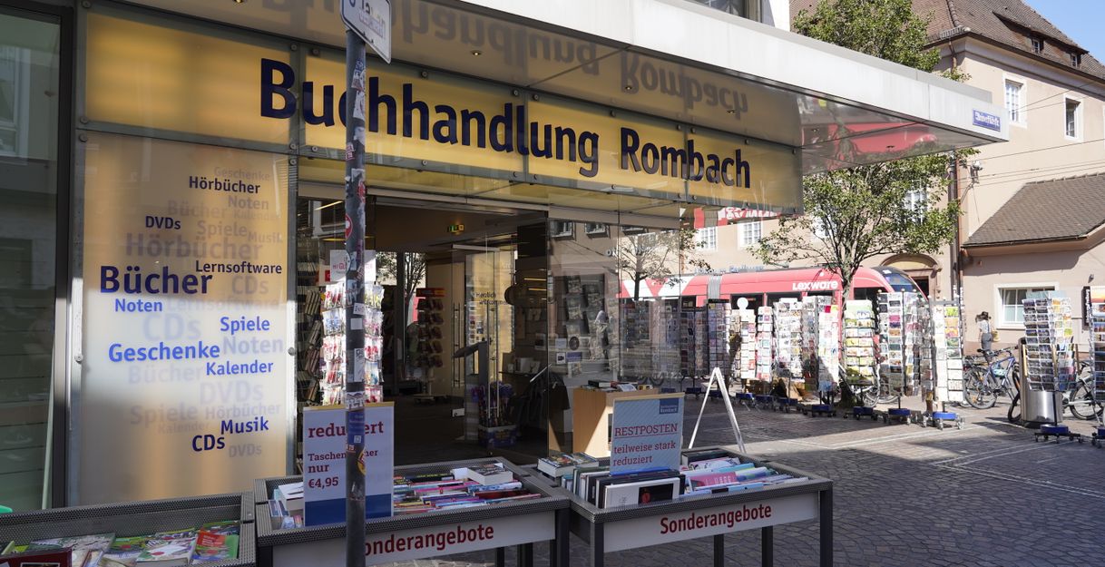 Eingang der Buchhandlung Rombach mit Sonderangeboten und Postkartenständern.