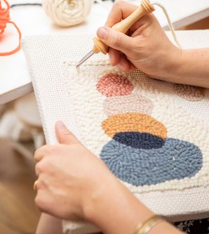 zwei Hände beim Knüpfen eines Wandteppichs mit der Punch-Needle