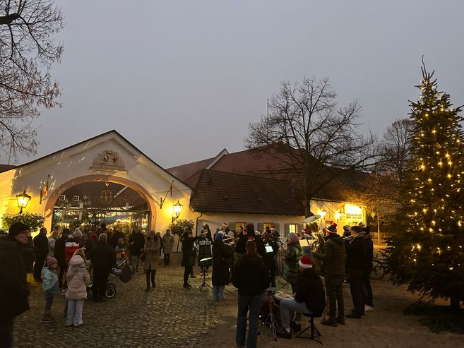 Tor der Hotel Schloss Reinach mit weihnachtlicher Beleuchtung und einer Blaskapelle davor