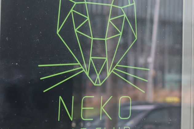 Plakat des Neko Bar Clubs mit geometrischem Katzenkopf und Textinformationen.