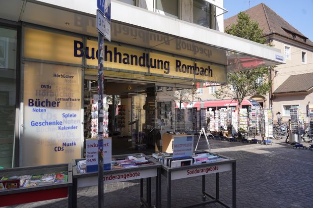 Eingang der Buchhandlung Rombach mit Sonderangeboten und Postkartenständern.