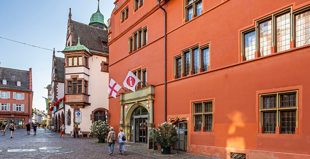 Außenansicht Altes Rathaus mit roter Fassade, in dem der Eingang der Tourist Information liegt. 